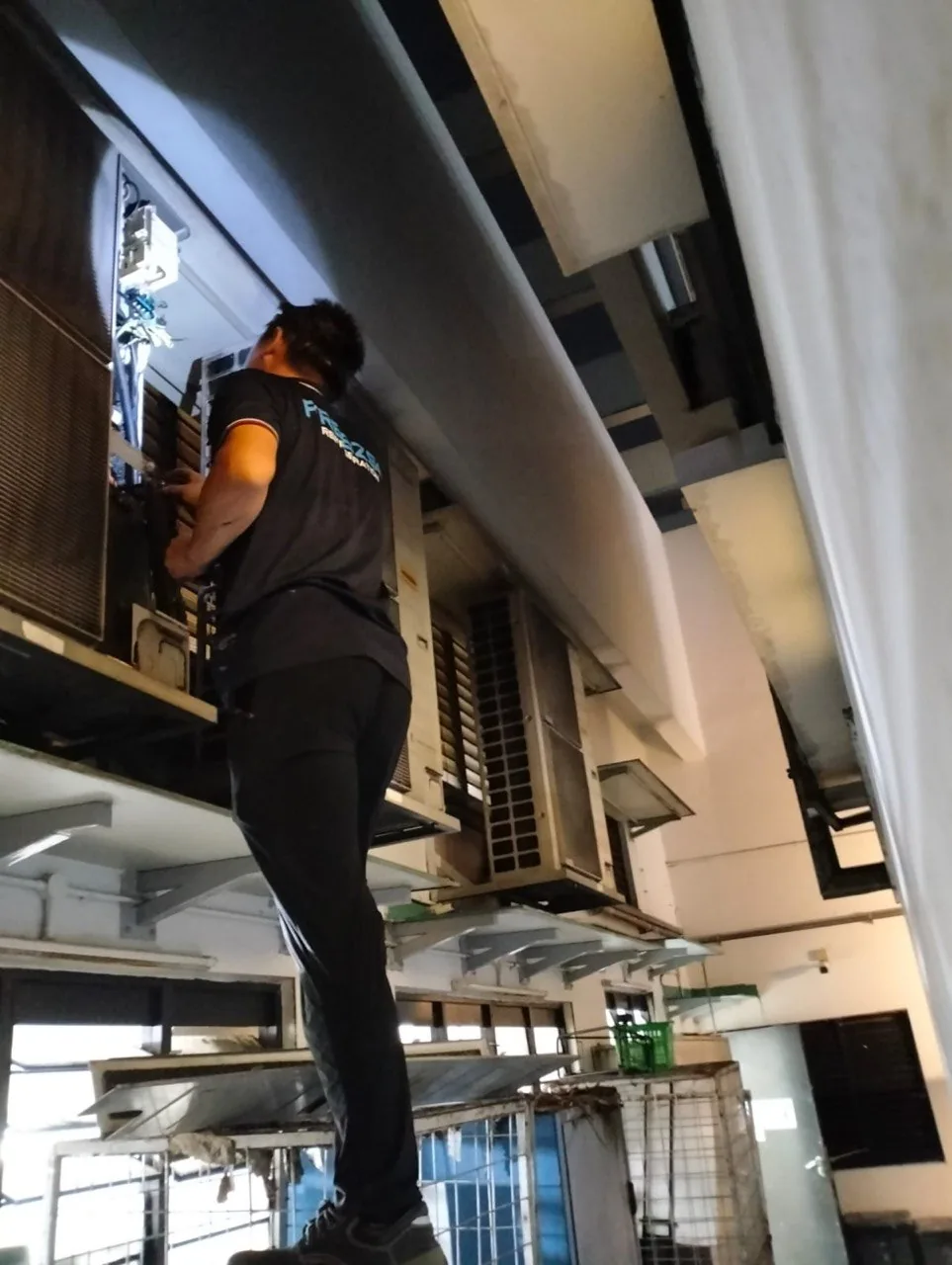 Freezso technician working on an outdoor air-conditioning condenser unit in Singapore